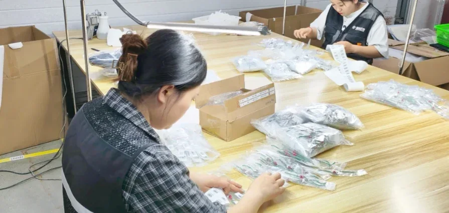 Workers applying protective packaging at a shared company workstation