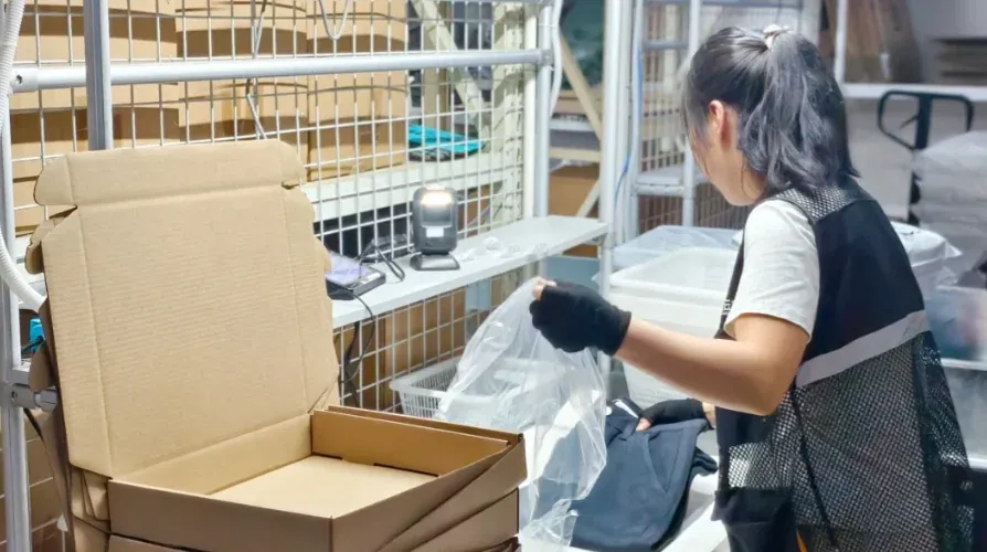Worker preparing protective packing material beside a carton