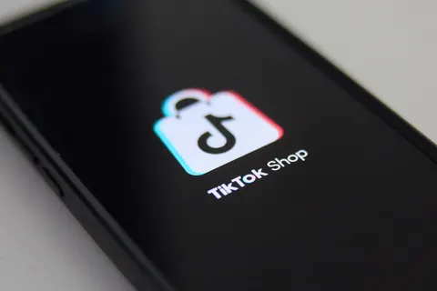 A close-up of a smartphone screen displaying the TikTok Shop app icon, featuring a shopping bag with the TikTok logo, on a dark background.