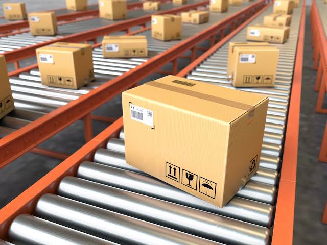 A 3D render of multiple cardboard boxes with shipping labels moving along parallel conveyor belts in a warehouse, representing a multichannel prep workflow.