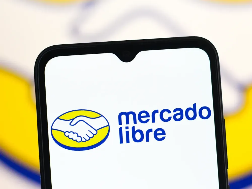 A smartphone screen displaying the official Mercado Libre logo, featuring a yellow oval with a handshake icon and the blue text "mercado libre."